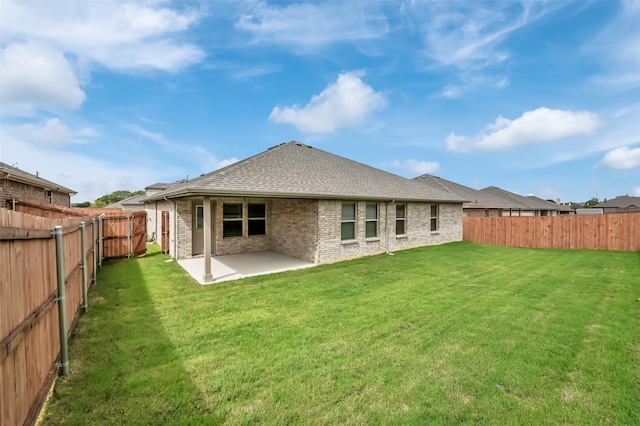 rear view of house with a fenced backyard, a yard, brick siding, a shingled roof, and a patio