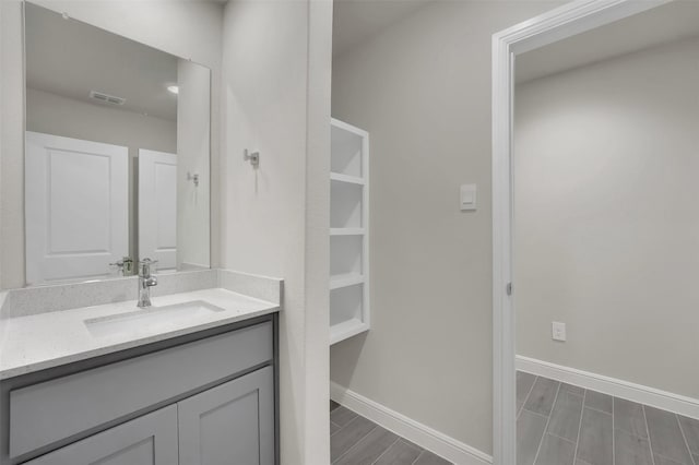 bathroom featuring baseboards, visible vents, wood tiled floor, and vanity