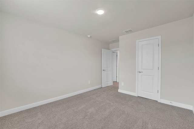 spare room featuring carpet, visible vents, and baseboards