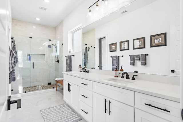 bathroom featuring a sink, a shower stall, marble finish floor, double vanity, and visible vents