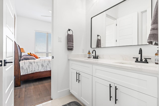 ensuite bathroom featuring double vanity, a sink, connected bathroom, and baseboards