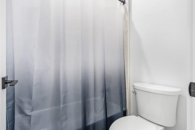 full bath with toilet and a shower with shower curtain