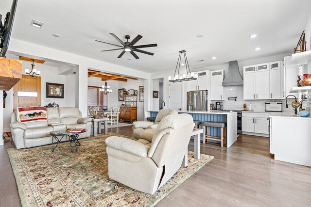 living room featuring recessed lighting, light wood finished floors, visible vents, a toaster, and ceiling fan with notable chandelier
