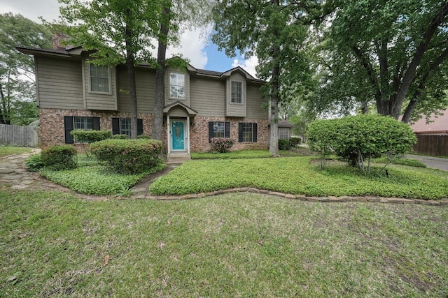 view of front of home with fence, a front yard, and brick siding