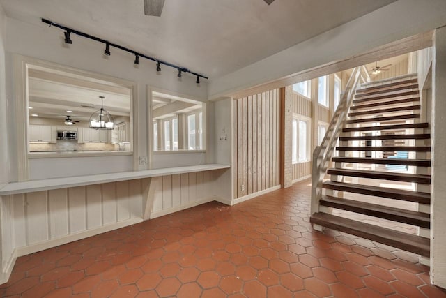 stairway featuring tile patterned flooring, track lighting, ceiling fan, and baseboards