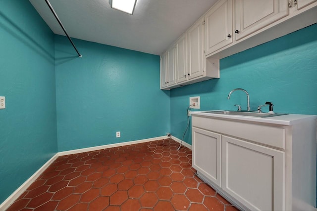 washroom featuring a sink, cabinet space, hookup for a washing machine, baseboards, and dark tile patterned flooring