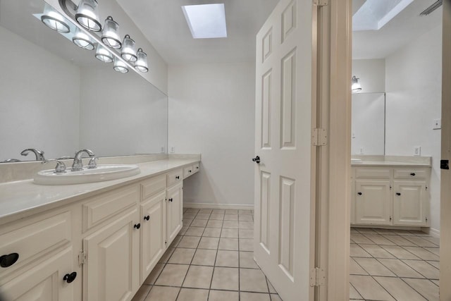 bathroom with tile patterned floors, vanity, baseboards, and a skylight