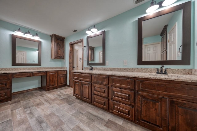 bathroom with double vanity, a sink, and visible vents
