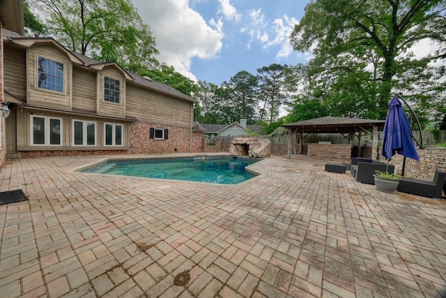 view of pool featuring a patio area, a fenced in pool, a fenced backyard, an outdoor kitchen, and a gazebo
