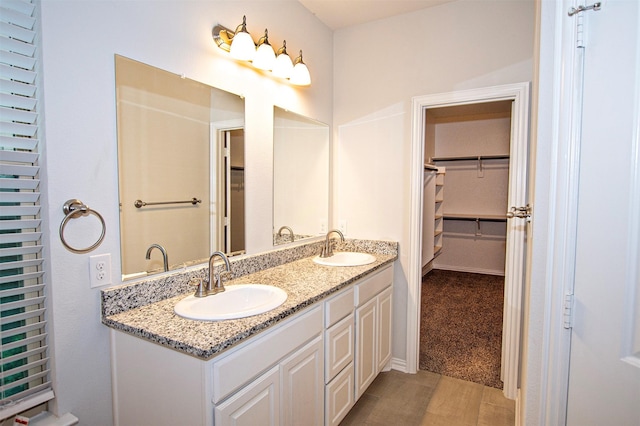 2811 W Washington St, Denison, TX 75020 - bathroom with a spacious closet, wood finished floors, double vanity, and a sink