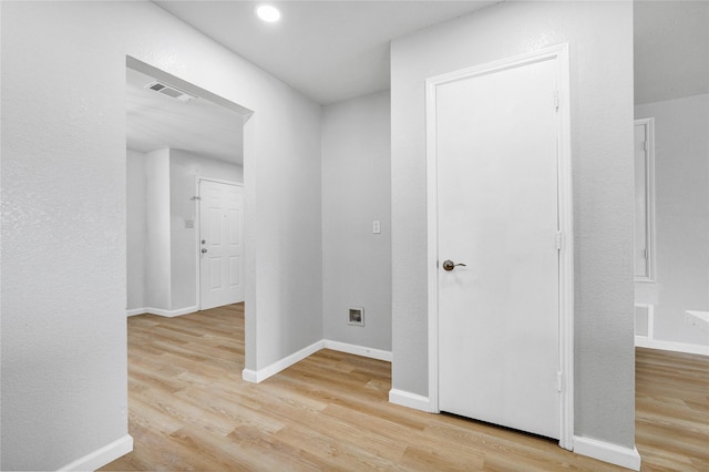 corridor featuring visible vents, baseboards, and light wood-style floors