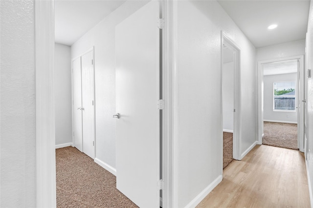 corridor with recessed lighting, light wood-style flooring, light colored carpet, and baseboards