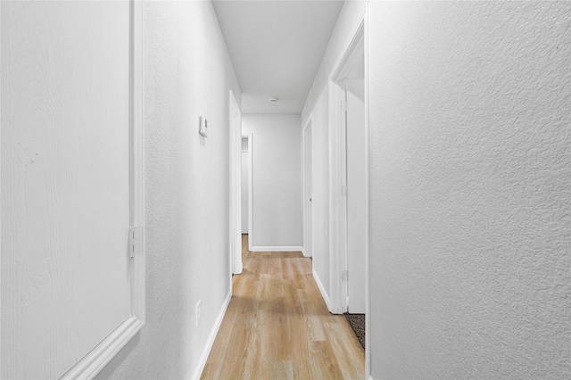 hall with baseboards and light wood-type flooring
