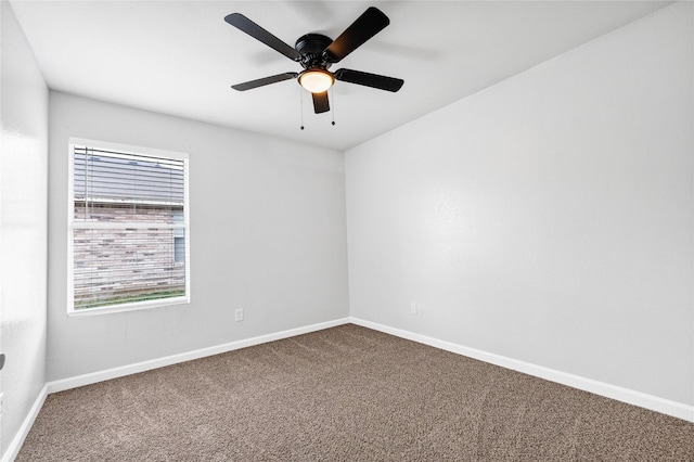 empty room with ceiling fan, dark colored carpet, and baseboards