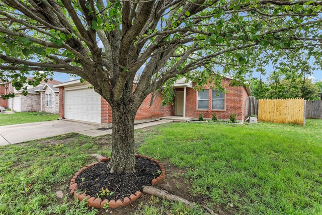 view of front of home with brick siding, fence, a front yard, and concrete driveway