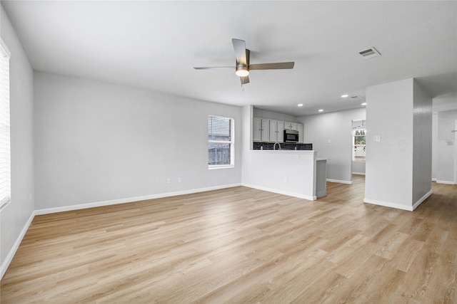 unfurnished living room featuring baseboards, visible vents, a ceiling fan, and light wood-style flooring
