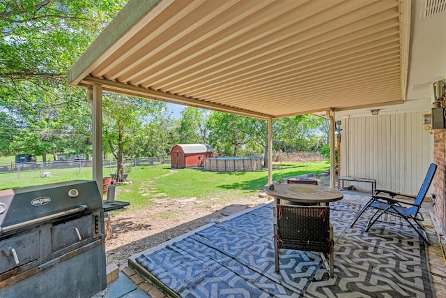 view of patio with grilling area, a fenced backyard, and a storage unit