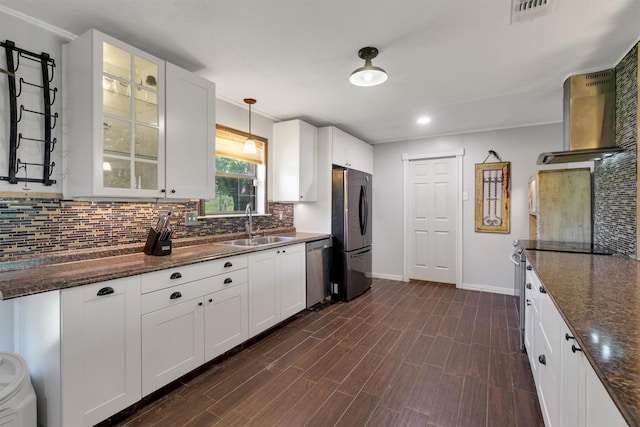 kitchen with wall chimney range hood, a sink, dishwasher, freestanding refrigerator, and visible vents