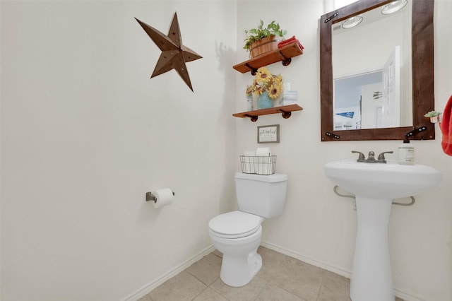 half bathroom featuring tile patterned floors, baseboards, and toilet