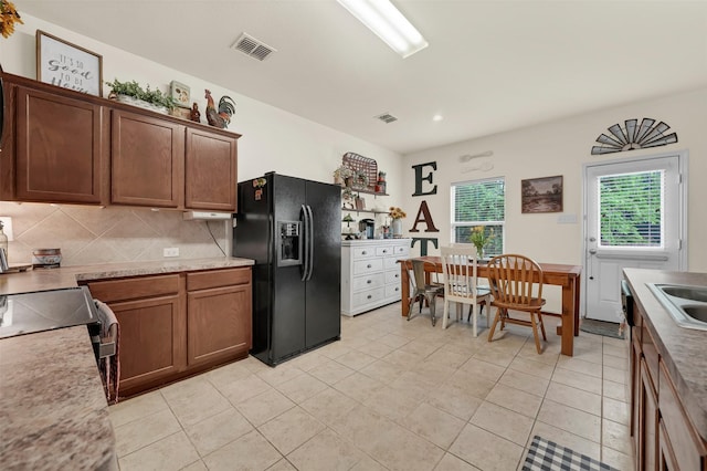 kitchen with light tile patterned floors, backsplash, visible vents, and black fridge with ice dispenser