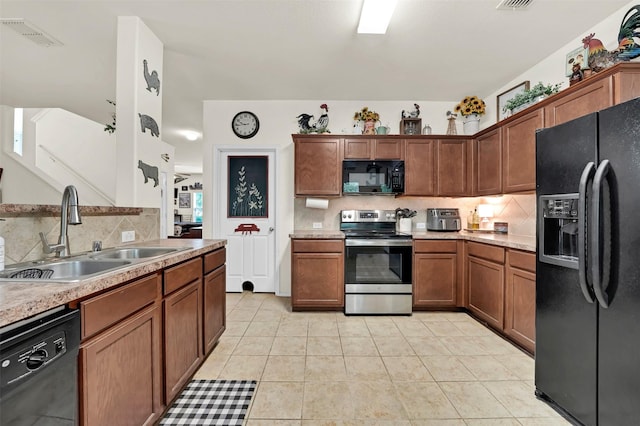 kitchen with tasteful backsplash, a sink, light countertops, black appliances, and light tile patterned flooring