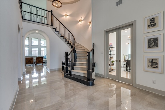 foyer entrance featuring a high ceiling, visible vents, stairway, and french doors