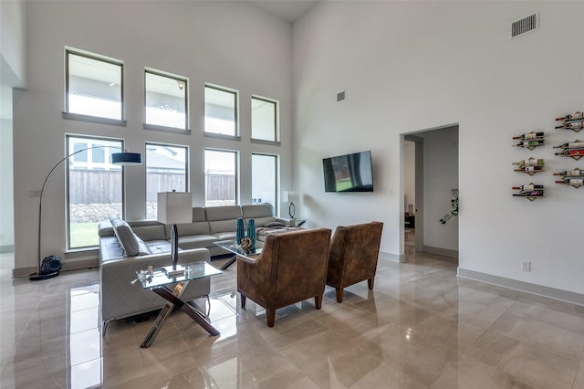 living room with a towering ceiling, visible vents, and baseboards