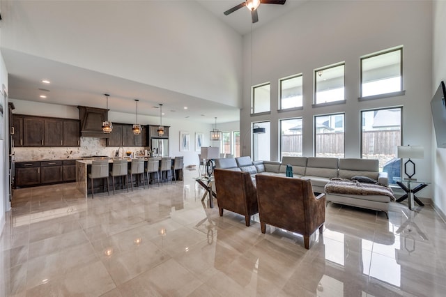 living room with a ceiling fan and a high ceiling