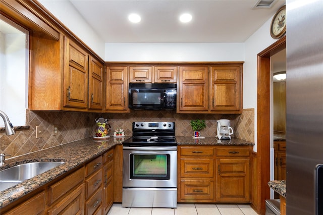 1515 Brighton Dr, Carrollton, TX 75007 - kitchen featuring dark stone counters, brown cabinets, a sink, appliances with stainless steel finishes, and visible vents