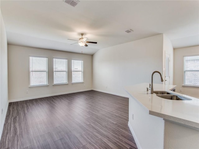 unfurnished living room with a sink, visible vents, baseboards, dark wood-style flooring, and a ceiling fan