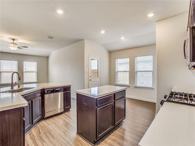 kitchen featuring light wood-style flooring, a sink, appliances with stainless steel finishes, ceiling fan, and an island with sink