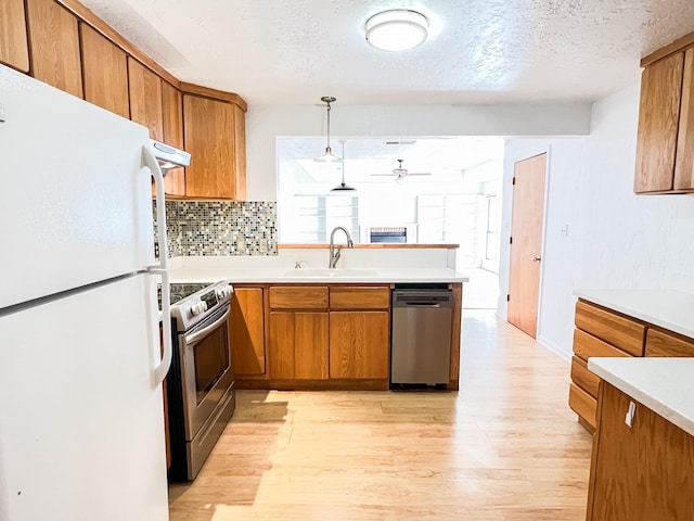 505 N Yosemite, Iowa Park, TX 76367 - kitchen featuring light wood finished floors, a sink, stainless steel appliances, brown cabinetry, and a ceiling fan