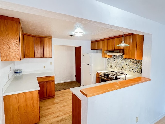 505 N Yosemite, Iowa Park, TX 76367 - kitchen with decorative backsplash, freestanding refrigerator, brown cabinetry, stainless steel electric range, and light wood finished floors