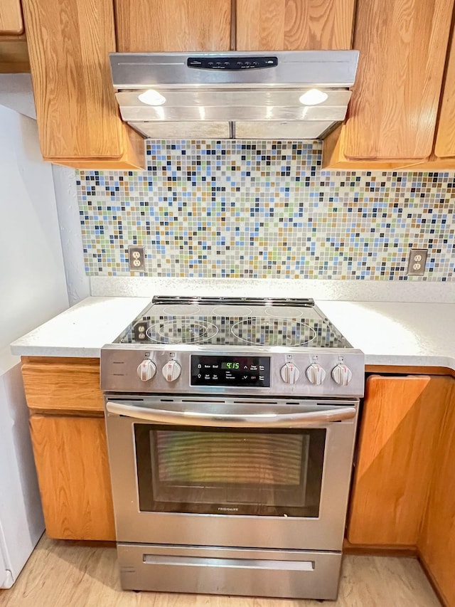 505 N Yosemite, Iowa Park, TX 76367 - kitchen featuring light wood-style flooring, under cabinet range hood, light countertops, backsplash, and stainless steel electric range