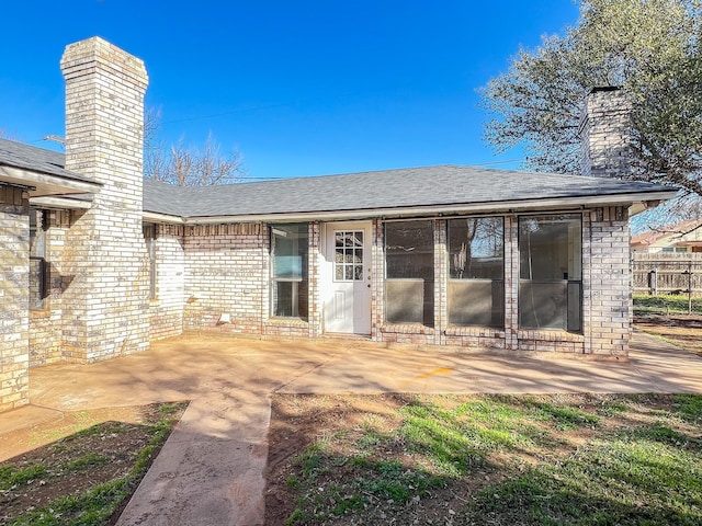 505 N Yosemite, Iowa Park, TX 76367 - back of house featuring a chimney, a patio area, a shingled roof, and brick siding