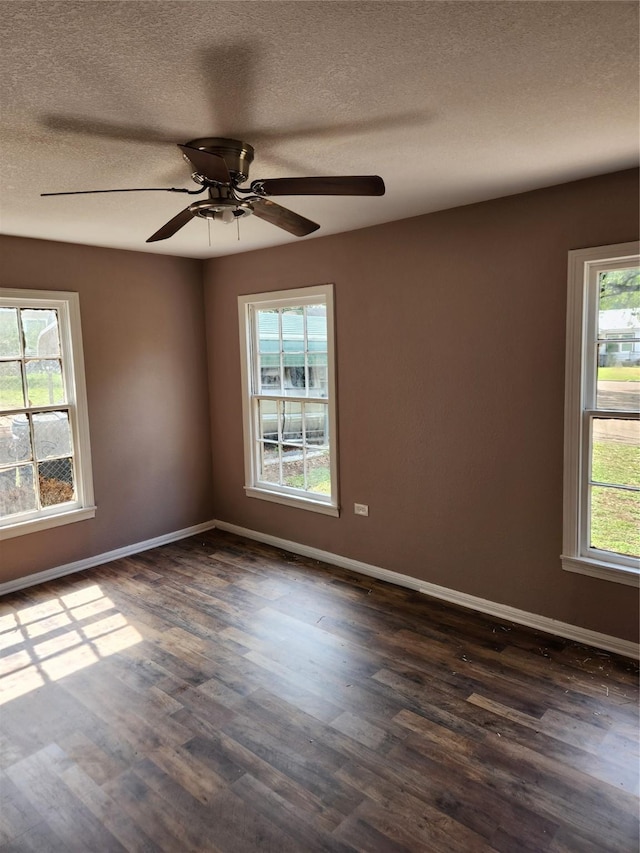 empty room with baseboards, ceiling fan, a textured ceiling, and dark wood-style flooring