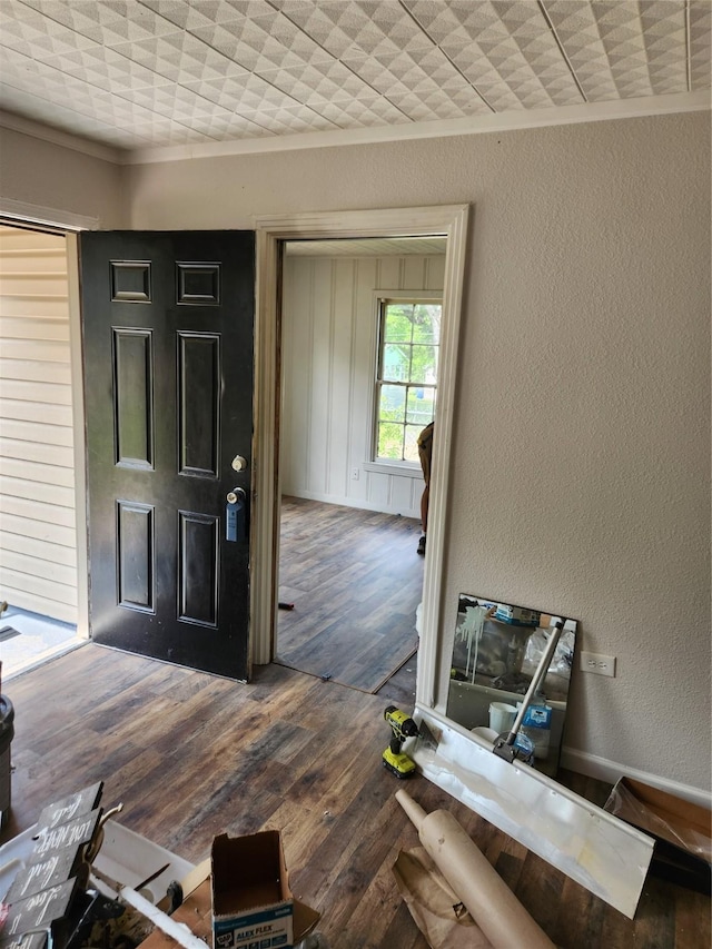 entrance foyer featuring ornamental molding, a textured wall, and wood finished floors