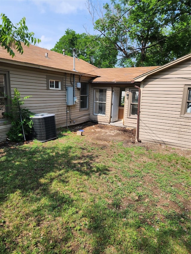 back of property featuring central AC and a yard