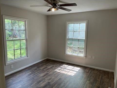 empty room with dark wood-style flooring, a wealth of natural light, and baseboards