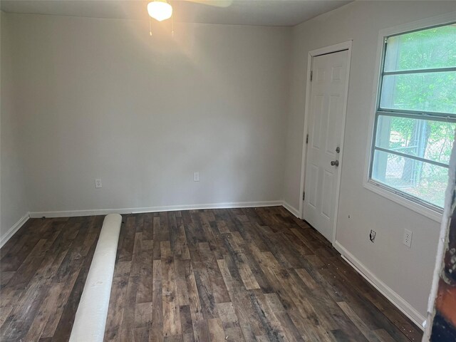 unfurnished room with baseboards, a ceiling fan, and dark wood-type flooring