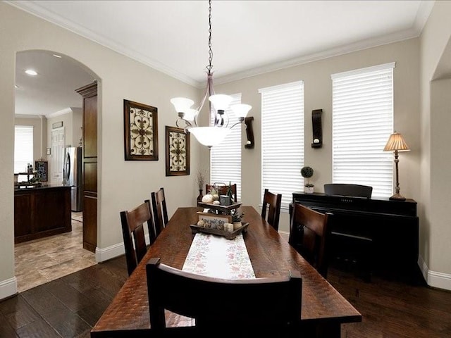 dining area with ornamental molding, arched walkways, an inviting chandelier, and wood finished floors