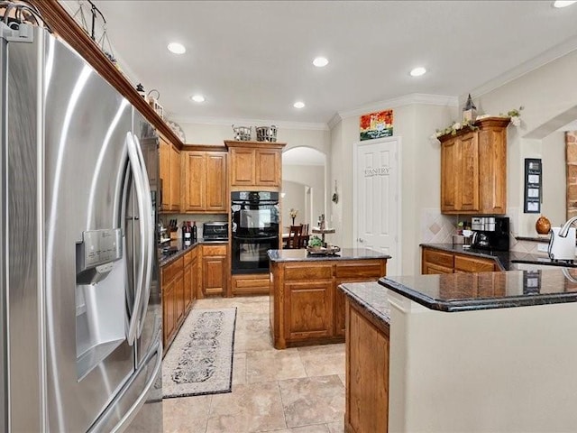 kitchen featuring brown cabinetry, a kitchen island, arched walkways, dobule oven black, and stainless steel fridge with ice dispenser