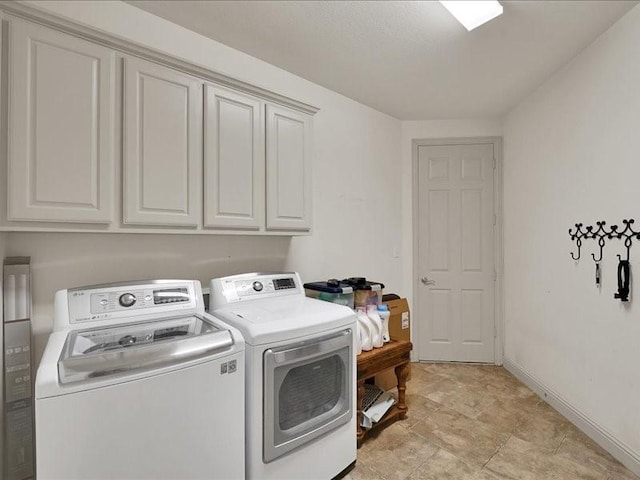 clothes washing area with baseboards, cabinet space, and washing machine and dryer
