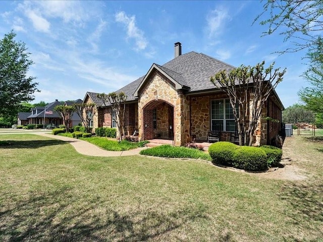 tudor house with a chimney, a front yard, and stone siding
