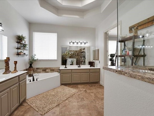 1043 Oak Creek Cir, Royse City, TX 75189 - bathroom featuring a garden tub, two vanities, and a tray ceiling