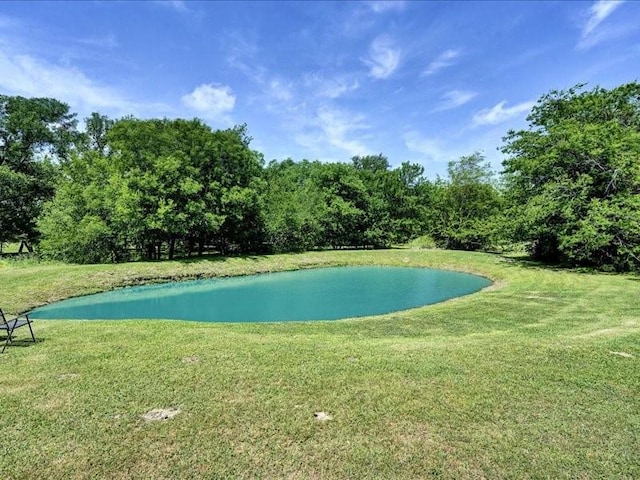view of swimming pool featuring a lawn and a water view