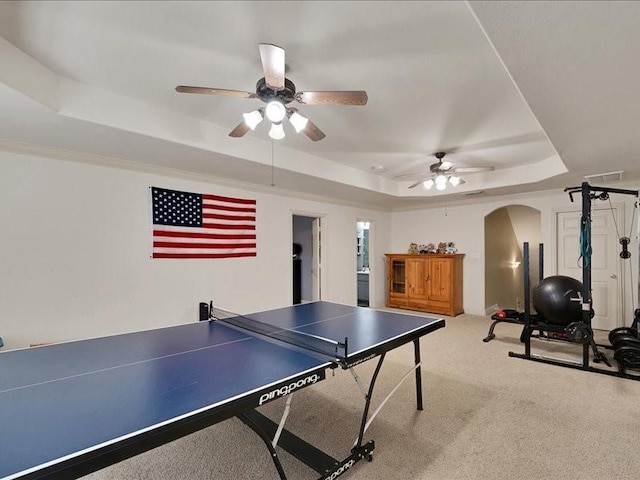 rec room featuring arched walkways, a ceiling fan, carpet floors, and a tray ceiling