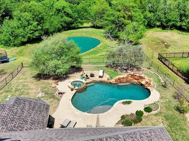 view of pool featuring a fenced backyard, a yard, and a pool with connected hot tub