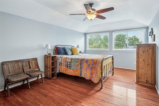 bedroom featuring a ceiling fan, vaulted ceiling, wood finished floors, and baseboards