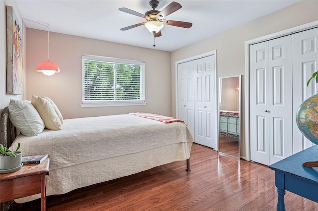 bedroom featuring wood finished floors, a ceiling fan, and two closets